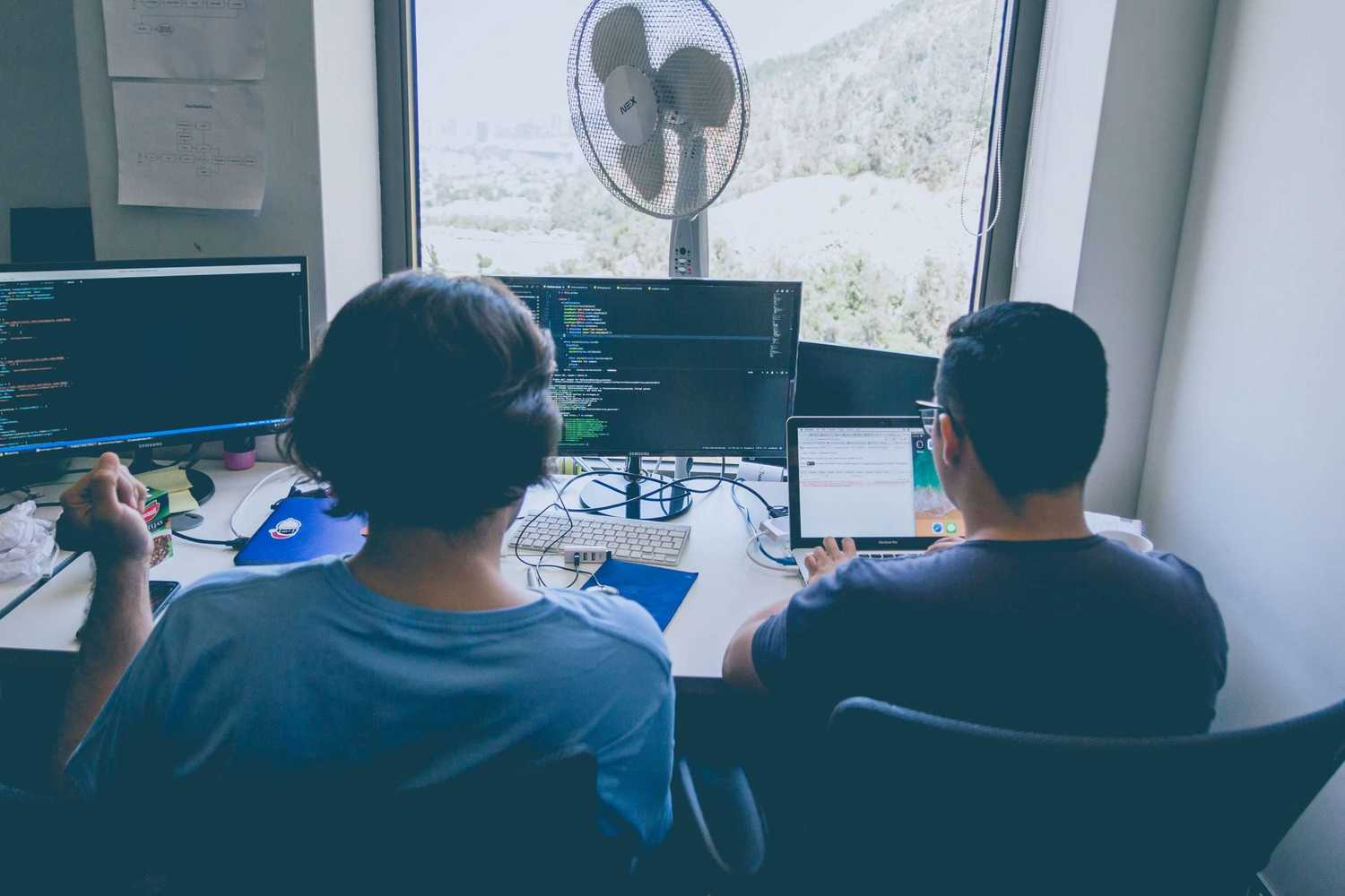 Two people pair programming at desk. Two people pair programming at desk.