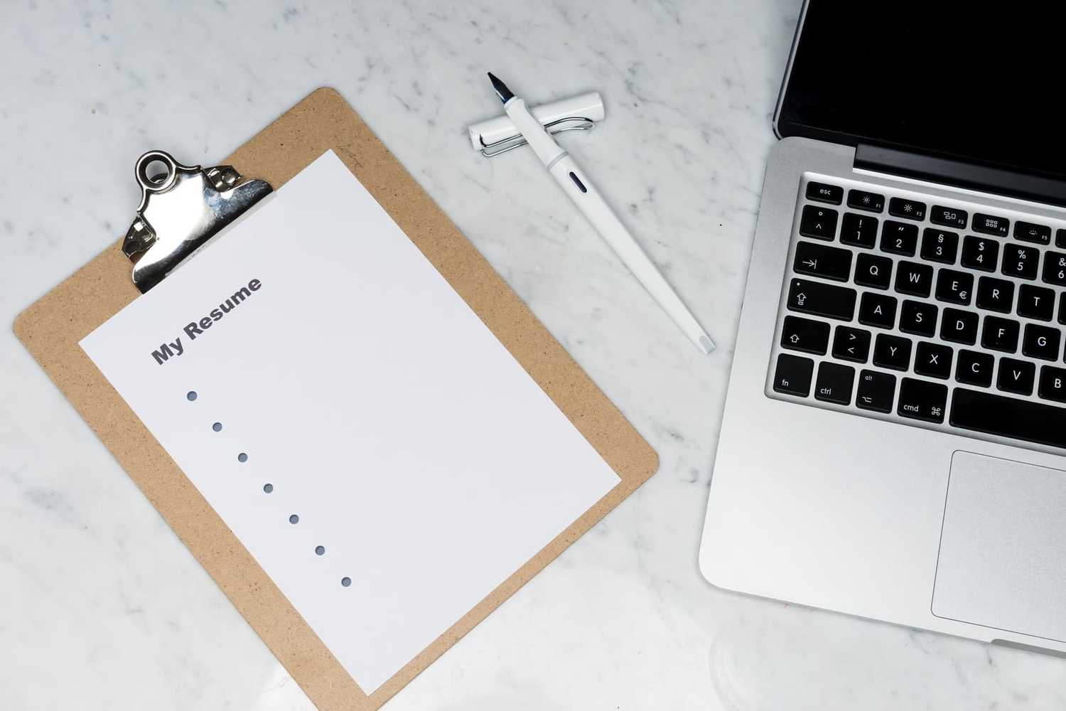 Clipboard with resume beside laptop Clipboard with resume beside laptop