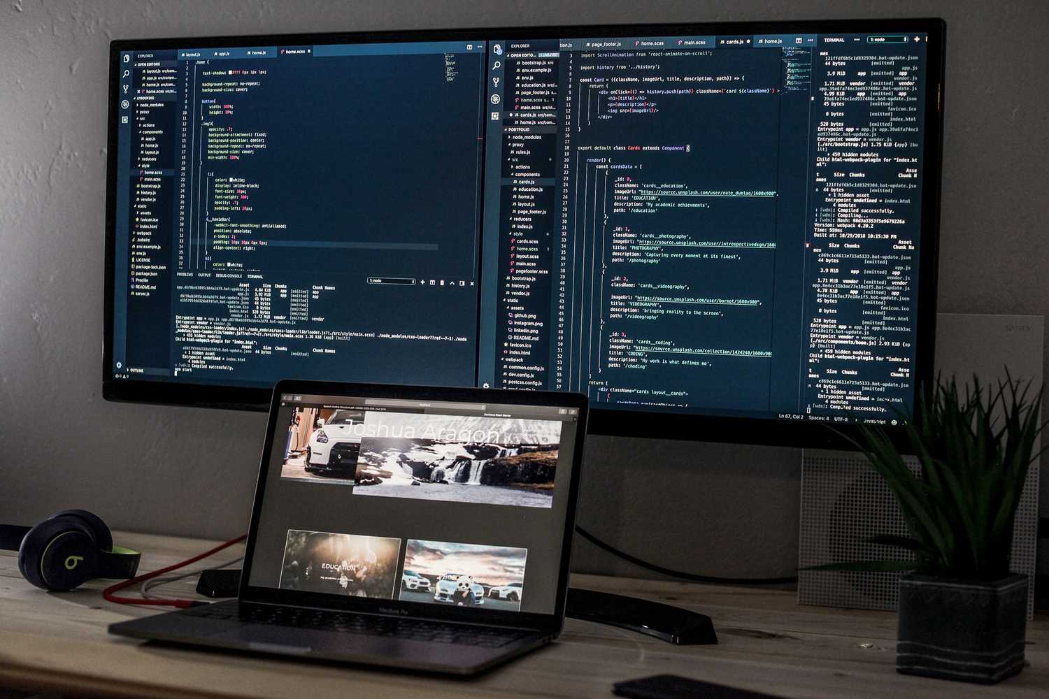 MacBook Pro on a desk in front of two large monitors