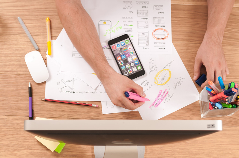 A photo of a desk with a computer, phone and desing mock ups by William Iven